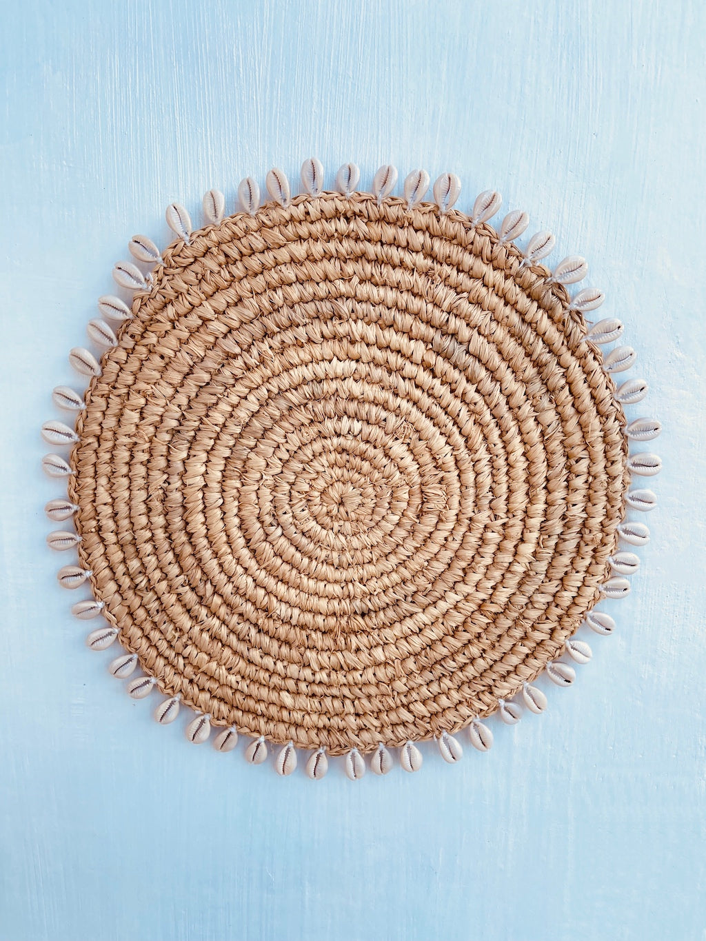 Round raffia placemat decorated with shells